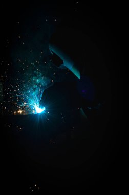 Kaynakçı, metal ekipman üretiminde kıvılcım çıkarmak için meşale kullanır. Profesyonel kaynak ustası.