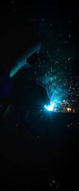 Kaynakçı, metal ekipman üretiminde kıvılcım çıkarmak için meşale kullanır. Profesyonel kaynak ustası.