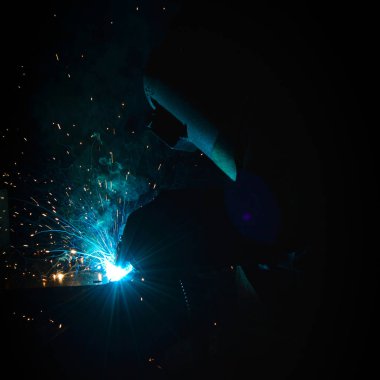 Kaynakçı, metal ekipman üretiminde kıvılcım çıkarmak için meşale kullanır. Profesyonel kaynak ustası.