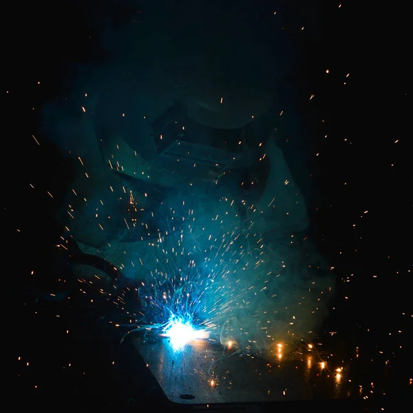 Kaynakçı, metal ekipman üretiminde kıvılcım çıkarmak için meşale kullanır. Profesyonel kaynak ustası.