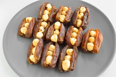 Organik taze besleyici kurutulmuş hurma, tarihin içine yerleştirilmiş fındık ve jool taneleri, gri bir tabakta.