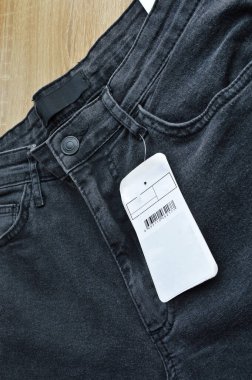 Fermuar cebi ve düğmeleri siyah kot pantolon ve boş etiket kağıdı, ahşap zeminde.