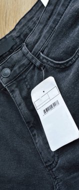 Fermuar cebi ve düğmeleri siyah kot pantolon ve boş etiket kağıdı, ahşap zeminde.