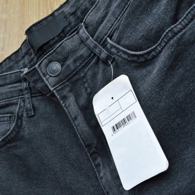 Fermuar cebi ve düğmeleri siyah kot pantolon ve boş etiket kağıdı, ahşap zeminde.