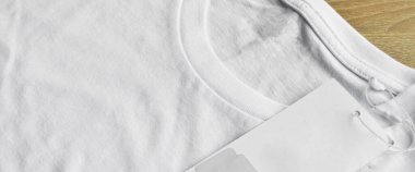 Beyaz temiz mavi tişört ve boş etiket, ahşap zeminde.