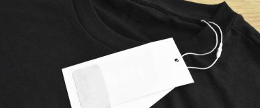 Siyah temiz mavi tişört ve boş etiket, ahşap zeminde.