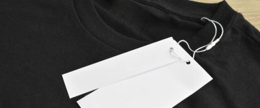 Siyah temiz mavi tişört ve boş etiket, ahşap zeminde.