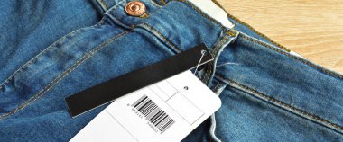 Fermuar cebi ve düğmeleri kot pantolon ve boş etiket kağıdı, ahşap zeminde.