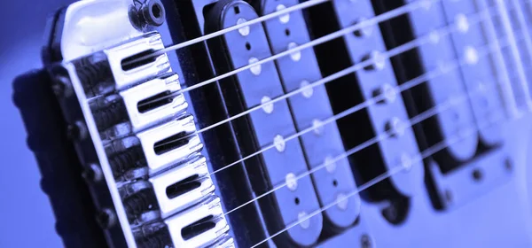 Electric guitar bridge, strings and pickup. Detail close-up view of guitar pickup in blue color. Music instrument