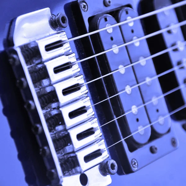 Electric guitar bridge, strings and pickup. Detail close-up view of guitar pickup in blue color. Music instrument