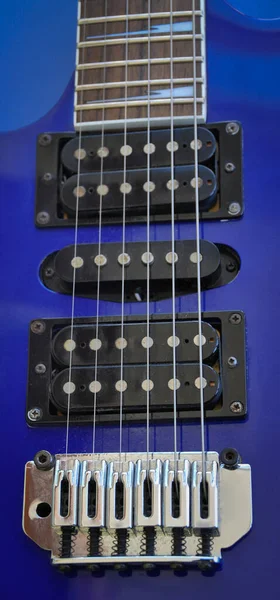 Electric guitar bridge, strings and pickup. Detail close-up view of guitar pickup in blue color. Music instrument