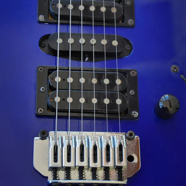 Electric guitar bridge, strings and pickup. Detail close-up view of guitar pickup in blue color. Music instrument