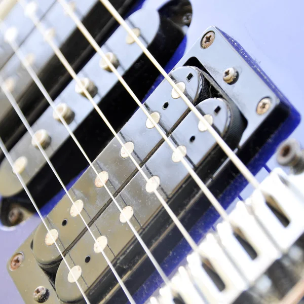 Electric guitar bridge, strings and pickup. Detail close-up view of guitar pickup in blue color. Music instrument