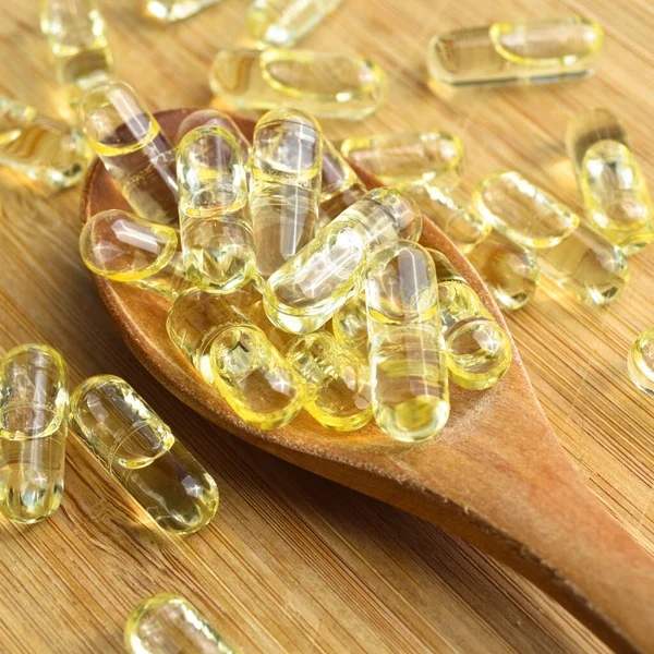 Gelbes Fischöl Ovale Tablette Tabletten Holzlöffel Auf Bambus Schneidebrett Medizinische — Stockfoto