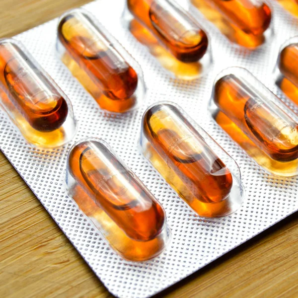 Pomarańczowa Kapsułka Tabletki Izolowane Tle Drewna Kapsułki Medyczne Pigułki — Zdjęcie stockowe