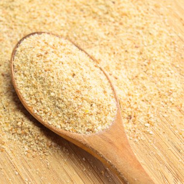 Taze ve lezzetli ekmek kırıntıları kahverengi bambu kesme tahtasının üzerinde tahta kaşıkta galeta unu.