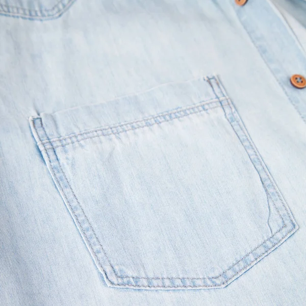 Light blue denim shirt, pocket and button detail, close-up blue jean shirt