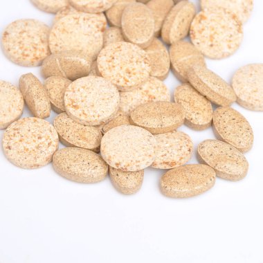 Beyaz arka planda izole edilmiş bej oval ve yuvarlak tablet haplar, tıbbi oval haplar