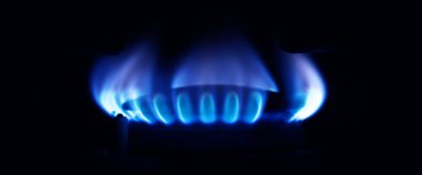 Mutfakta gaz ocağı yanıyor, siyah arka planda mavi alevler izole edilmiş.