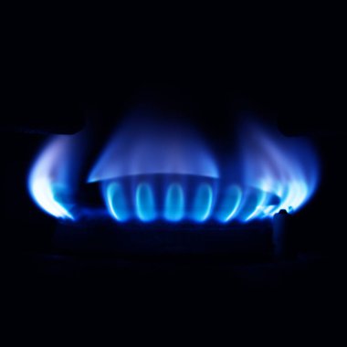 Mutfakta gaz ocağı yanıyor, siyah arka planda mavi alevler izole edilmiş.