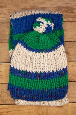 El yapımı yün örgü, eski ahşap arka planda izole edilmiş mavi şapka ve eşarp.