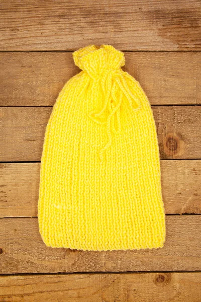 Handmade wool knitted winter light yellow hat isolated on wooden background