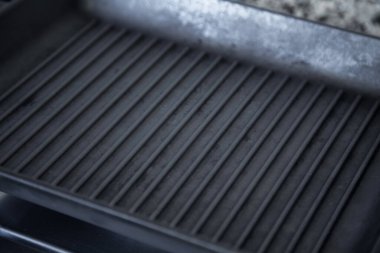 Boş siyah döküm, modern bir mutfakta gaz ocağında ağır demir ızgara tavası.