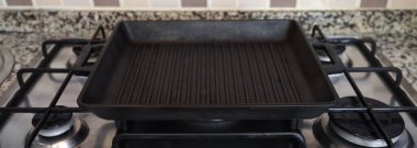 Boş siyah döküm, modern bir mutfakta gaz ocağında ağır demir ızgara tavası.