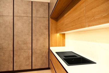 Modern kahverengi meşe ağacı mutfak malzemeleri ve şık granit siyah lavabo.