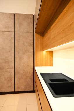 Modern kahverengi meşe ağacı mutfak malzemeleri ve şık granit siyah lavabo.