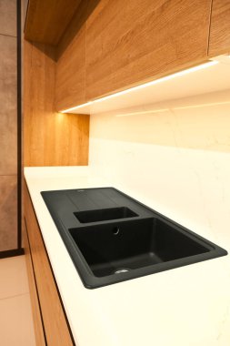 Modern kahverengi meşe ağacı mutfak malzemeleri ve şık granit siyah lavabo.
