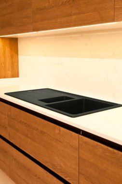 Modern kahverengi meşe ağacı mutfak malzemeleri ve şık granit siyah lavabo.