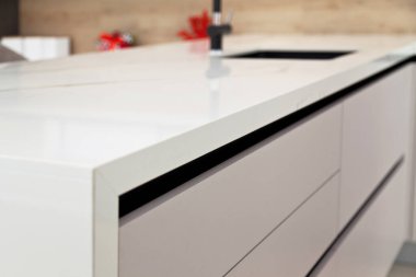 Modern beyaz laquer ve dişbudak ağacı ahşap mutfak dolabı ekipmanları ve beyaz granit tezgahta siyah musluk.