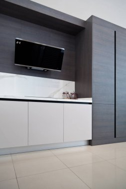 Modern gri beyaz laquer ahşap mutfak ekipmanı ve siyah elektrikli soba ve beyaz granit tezgahta kaput