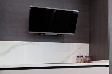 Modern gri beyaz laquer ahşap mutfak ekipmanı ve siyah elektrikli soba ve beyaz granit tezgahta kaput