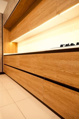 Modern kahverengi meşe ağacından mutfak malzemeleri, şık beyaz granit tezgah ve bir evde cam gaz sobası.