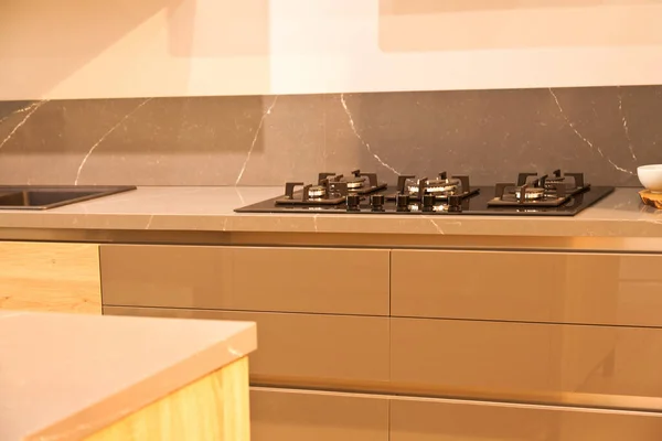 モダンな茶色のオークキッチンキャビネット機器 スタイリッシュな白い花崗岩のカウンタートップと家の中のガラスガスストーブ — ストック写真