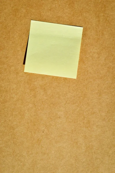 Square sticky yellow note paper on beige and brown cardboard paper