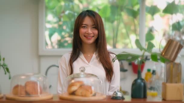 Mladá asijská žena barista pocit šťastný úsměv v městské kavárně. Malý podnikatel majitel žena v zástěře relaxovat úsměv při pohledu do kamery stojící u pultu v kavárně — Stock video