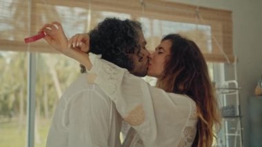 Genç, mutlu, evli çift dans ediyor. Birlikte gülüyorlar. Evde yemek pişiriyorlar. Kaygısız, neşeli karı koca, Boho tarzı mutfakta sağlıklı kahvaltı hazırlıyorlar.