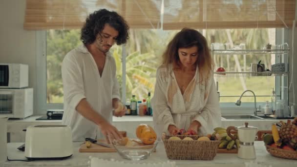 Joven feliz pareja casada activa bailando riendo juntos cocinando comidas en casa, sin preocupaciones alegre marido y esposa se divierten cocinando comida saludable para el desayuno en la cocina estilo boho — Vídeos de Stock