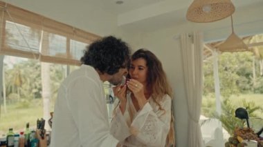 Genç, mutlu, evli çift dans ediyor. Birlikte gülüyorlar. Evde yemek pişiriyorlar. Kaygısız, neşeli karı koca, Boho tarzı mutfakta sağlıklı kahvaltı hazırlıyorlar.