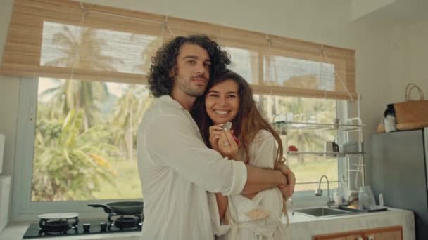 Junge glückliche aktive Ehepaare tanzen lachend zusammen und kochen zu Hause Mahlzeiten, unbeschwert fröhliche Eheleute haben Spaß beim Kochen gesunder Frühstücksspeisen in Boho-Küche — Stockvideo