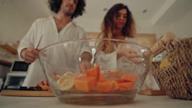 Genç, mutlu, evli çift dans ediyor. Birlikte gülüyorlar. Evde yemek pişiriyorlar. Kaygısız, neşeli karı koca, Boho tarzı mutfakta sağlıklı kahvaltı hazırlıyorlar.