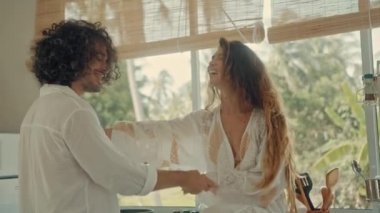Genç, mutlu, evli çift dans ediyor. Birlikte gülüyorlar. Evde yemek pişiriyorlar. Kaygısız, neşeli karı koca, Boho tarzı mutfakta sağlıklı kahvaltı hazırlıyorlar.