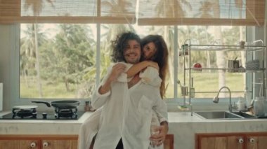 Genç, mutlu, evli çift dans ediyor. Birlikte gülüyorlar. Evde yemek pişiriyorlar. Kaygısız, neşeli karı koca, Boho tarzı mutfakta sağlıklı kahvaltı hazırlıyorlar.