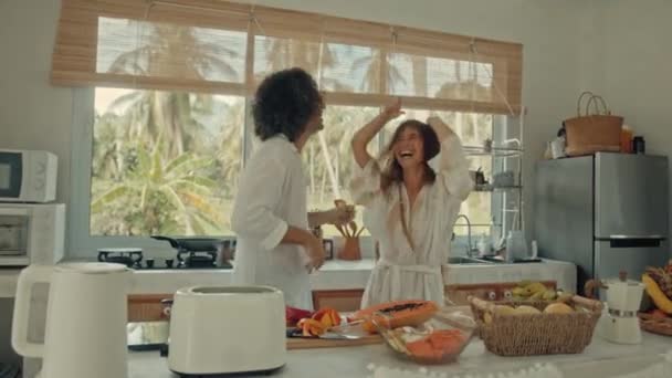 Jong gelukkig actief getrouwd stel dansen samen koken maaltijden thuis, zorgeloos vrolijke man en vrouw veel plezier koken gezond ontbijt eten in boho stijl keuken — Stockvideo