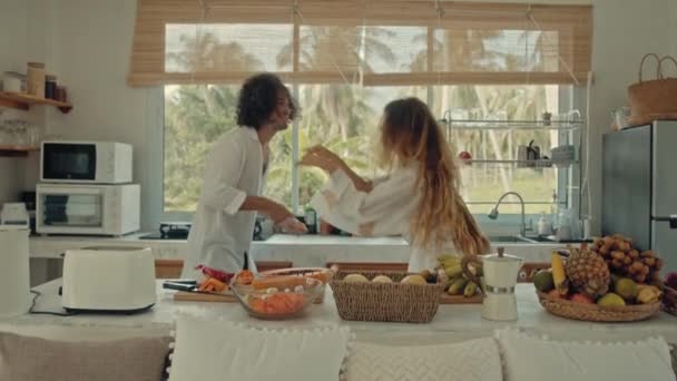 Jovem feliz casal ativo dançando risos juntos cozinhar refeições em casa, despreocupado marido alegre e esposa se divertir cozinhar comida saudável café da manhã na cozinha estilo boho — Vídeo de Stock