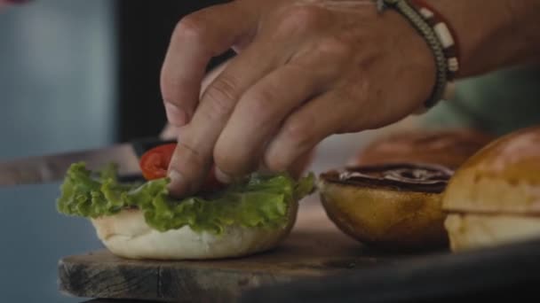 Chef preparando la hamburguesa. El primer plano - la mano del hombre unta la salsa la hamburguesa frita para la hamburguesa. Movimiento lento — Vídeo de stock