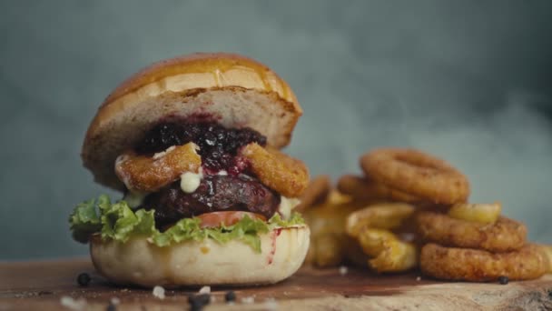Great Burger cu tăietură de vită, roșii, ciuperci și castraveți cu brânză topită pe o placă de lemn — Videoclip de stoc